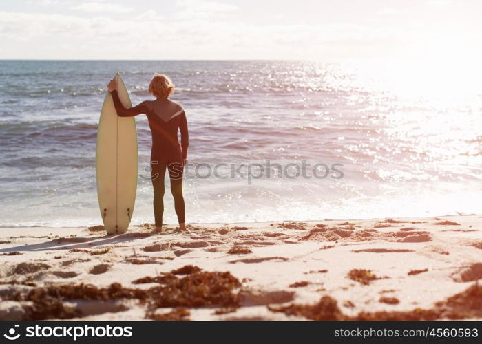 A surfer with his surfboard at the beach