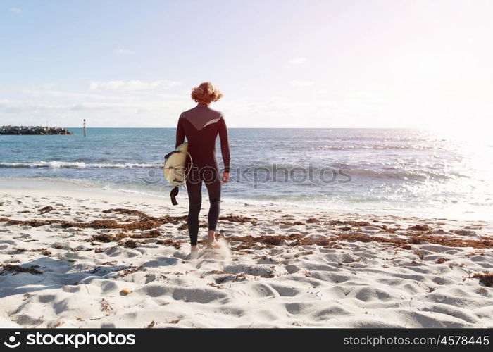 A surfer with his surfboard at the beach