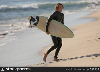 A surfer with his surfboard at the beach