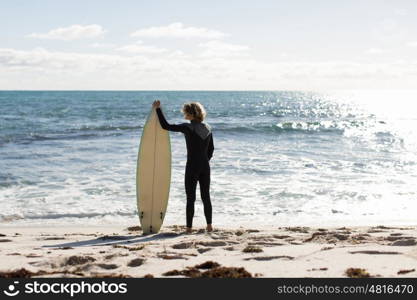 A surfer with his surfboard at the beach