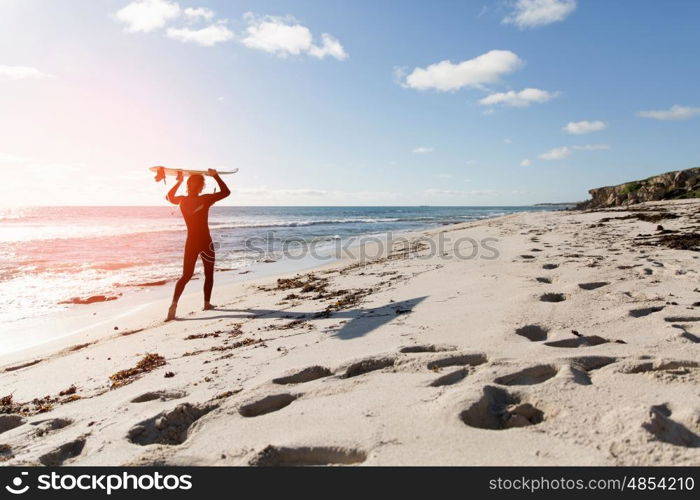 A surfer with his surfboard at the beach