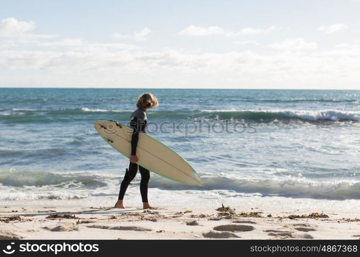 A surfer with his surfboard at the beach