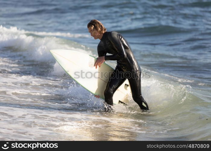 A surfer with his surfboard at the beach