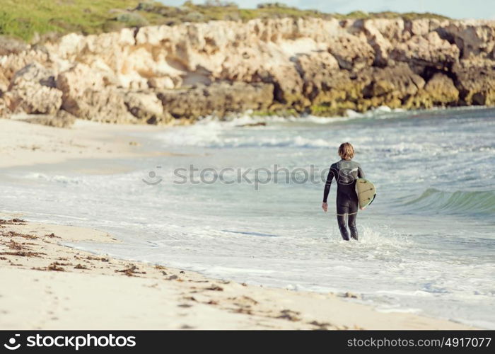 A surfer with his surfboard at the beach