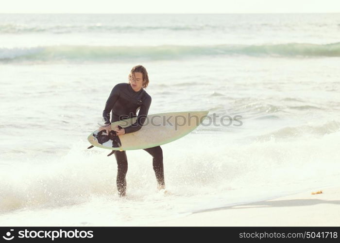 A surfer with his surfboard at the beach