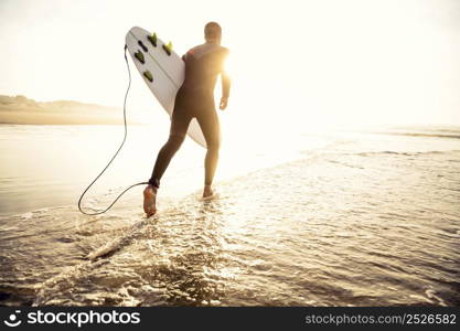 A surfer with his surfboard running to the waves