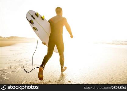 A surfer with his surfboard running to the waves