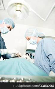 A surgeon working in a small operating room with an assistant