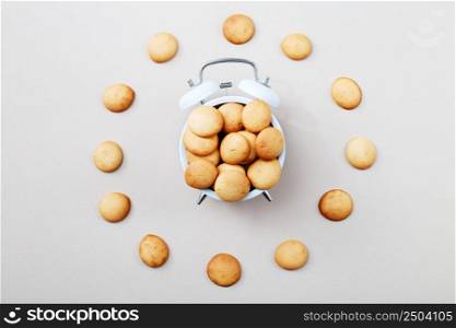 a sweet cookie in form of an alarm clock, time for breakfast or dessert concept. top view. mini pancakes background. sweet cookie in form of an alarm clock, time for breakfast or dessert concept. top view. mini pancakes background