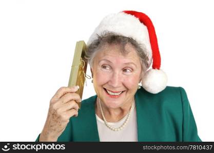 A sweet senior lady curious about her Christmas present. Isolated on white.