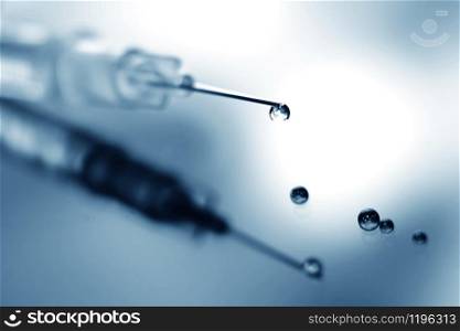 A syringe with a droplet of medicie on the needle