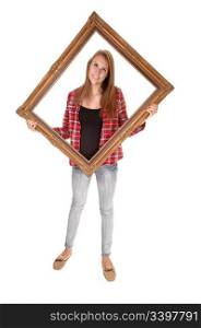 A tall pretty woman holding a picture frame for her upperbody, in jeans and a checkered shirt, over white.