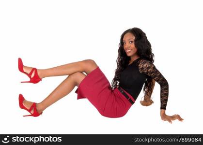 A tall slim African American woman in a red skirt and black blousesitting isolated for white background on the floor.