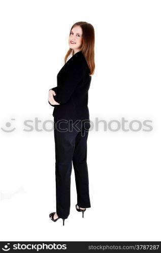 A tall slim young business woman standing in a black suit from the back,looking over her shoulder, isolated for white background.
