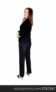 A tall slim young business woman standing in a black suit from the back,looking over her shoulder, isolated for white background.