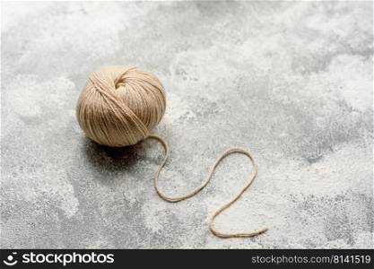 A tangle of beige-colored wool threads on a white concrete background. Manual knitting, hobby. A tangle of beige-colored wool threads on a white concrete background