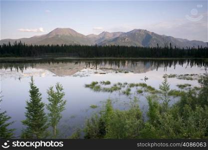 A tarn or lake just off Highway 2 reflects the Alaska mountain landscape