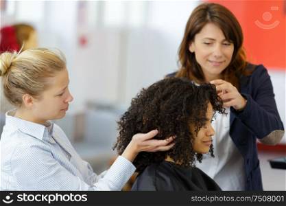 a teacher watching trainee hairdresser