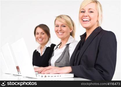 A team of three happy young businesswomen working on their laptops