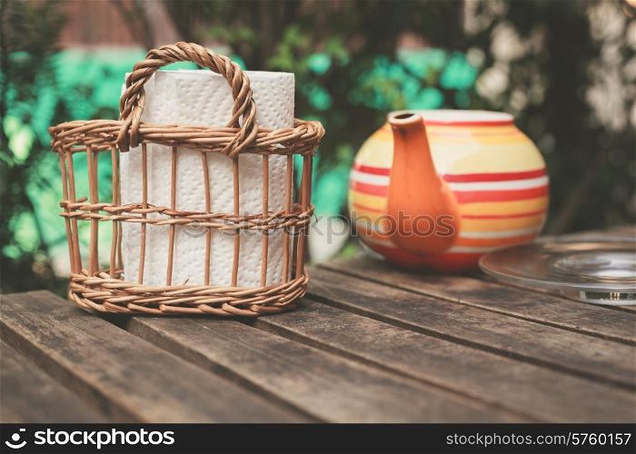 A teapot and some napkins on a wooden table outside
