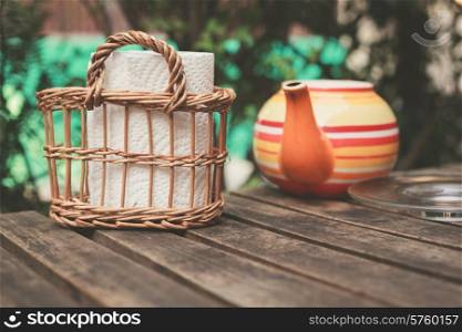 A teapot and some napkins on a wooden table outside