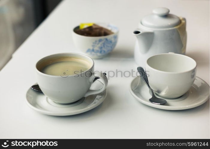 A teapot and two cups on a table in a cafe