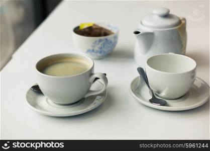 A teapot and two cups on a table in a cafe