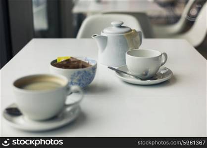 A teapot and two cups on a table in a cafe