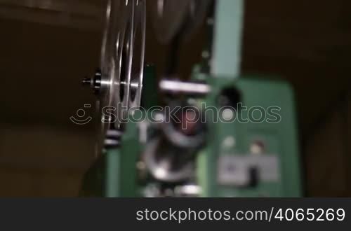 A technician projects a 16mm film. 16mm film projection cinema technical footage. Film Technician mounting a 16mm film reel in a film festival.