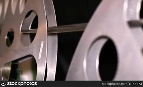 A technician rewinds 35mm film reels. 35mm film cinema technical footage. Film Technician mounting a 35mm film reel in a film festival.