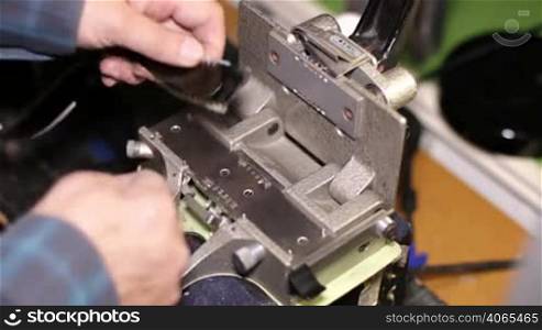 A technician splices a 35mm film reel with a film splicer machine. 35mm film cinema technical footage. Film Technician mounting a 35mm film reel in a film festival.