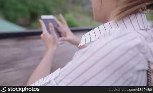 A technology obsessed blonde girl touching on smartphone moving skillfully on social media application, young active on holiday worker checking on friend&acute;s new feeds, missing people while on vacation