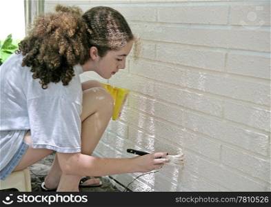 A teen girl painting house trim. Room for text.