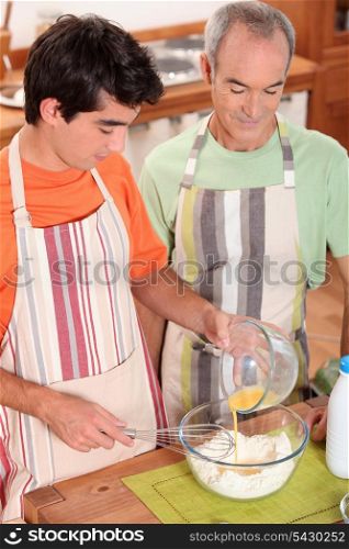 a teenage boy and a senior man making a cake