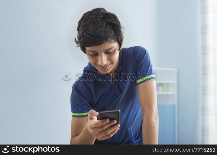 A TEENAGE BOY HAPPILY USING MOBILE PHONE AT HOME