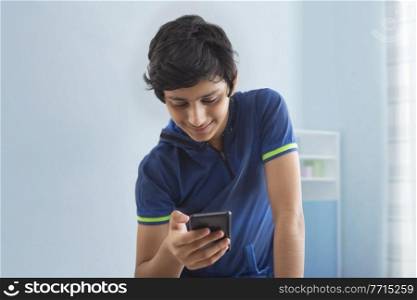 A TEENAGE BOY HAPPILY USING MOBILE PHONE AT HOME