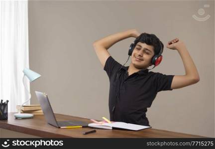 A TEENAGE BOY STRETCHING WHILE ATTENDING ONLINE CLASS