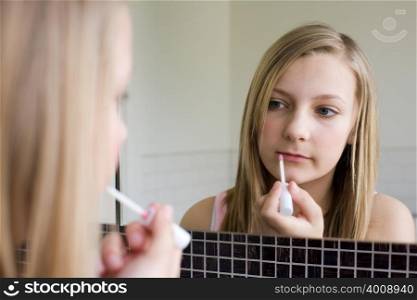 A teenage girl applying lipgloss