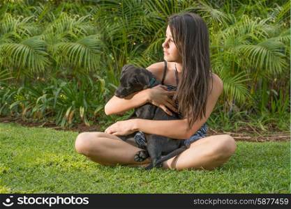 A teenage girl plays with her Labrador puppy outside on the lawn of their garden on a late summer afternoon.