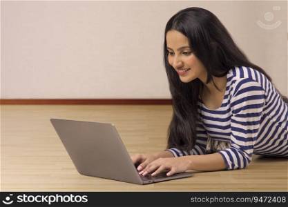 A TEENAGE GIRL RESTING ON FLOOR AND USING LAPTOP