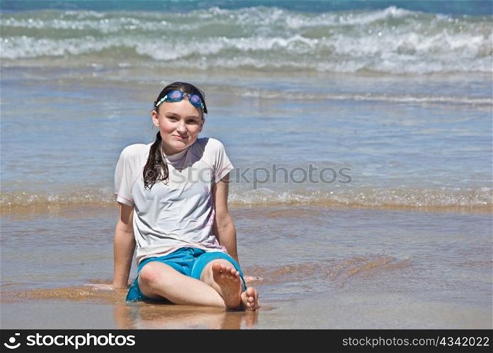 a teenage girl sits onn the beach