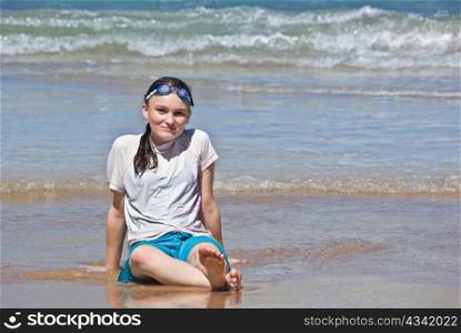 a teenage girl sits onn the beach