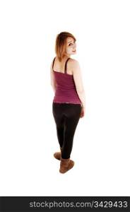 A teenage girl standing in the studio in black tights and brown boots,from the back and looking over her shoulder, over white background.