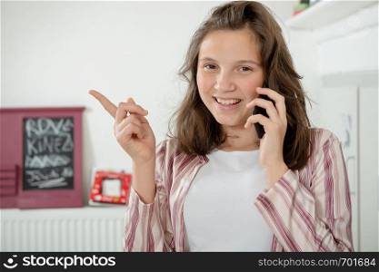 a teenage girl using a smartphone in the kitchen