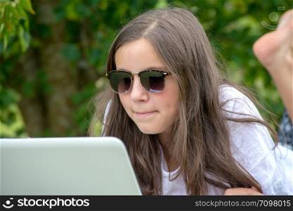 a teenage girl using laptop in the garden