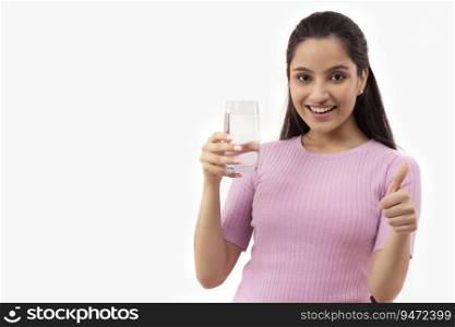 A TEENAGER POSING IN FRONT OF CAMERA HOLDING A GLASS OF WATER