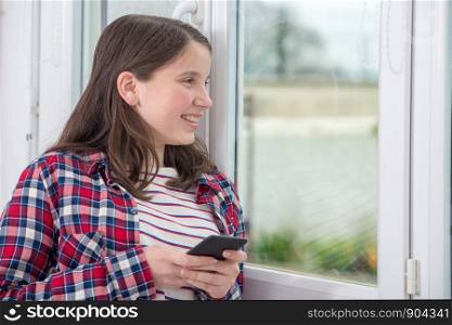a teenager using phone near the window