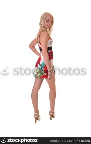 A teenager with a sweet smile standing in a colorful dress in thestudio, with her long blond hair, for white background.