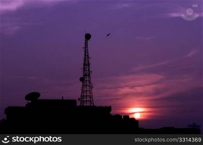A telecom tower against a tropical sunset. Modern versus nature