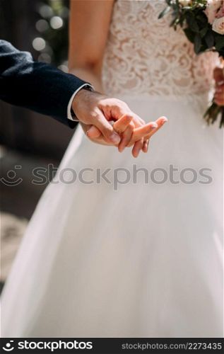 A tender photo of touching touches of the newlyweds.. Embracing the hands of the newlyweds on a sunny summer day 3801.